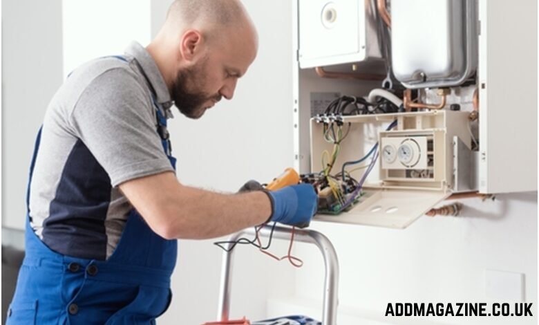 Engineer repairing a wall-mounted boiler with electrical tools